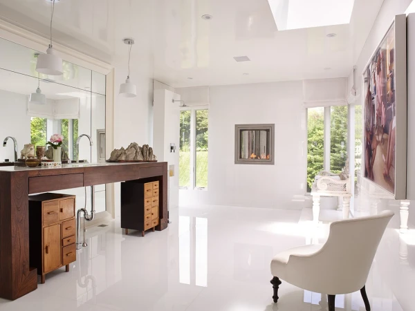 Bright bathroom interior with a dark wood vanity, white walls, light hardwood floors, a modern fireplace, and large picture on the wall.