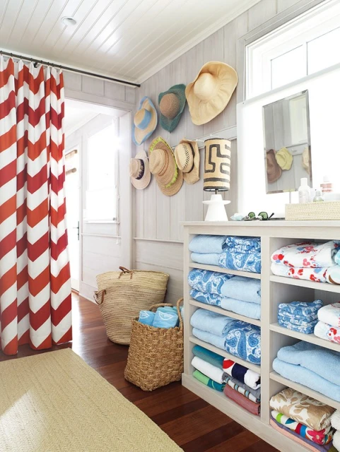 Interior view featuring a wall-mounted hat collection, stacked towels on shelves, and woven baskets for storage, creating a tidy aesthetic.