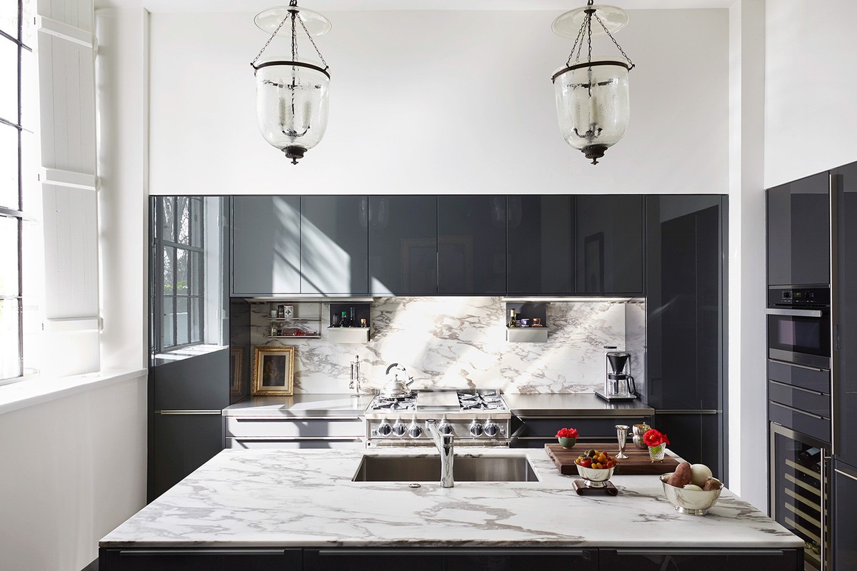 Contemporary kitchen interior featuring a marble island, grey cabinets, modern appliances, and elegant glass pendant lights.
