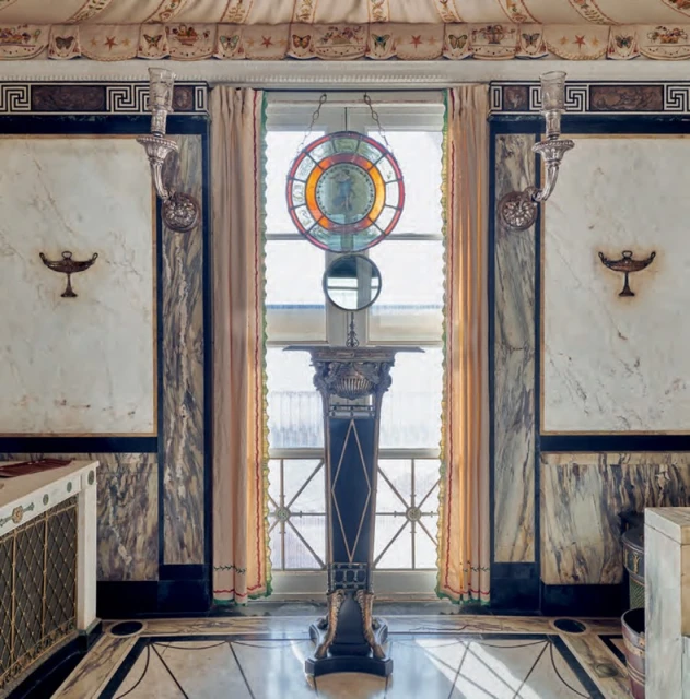 Ornate interior featuring marble walls, decorative window with stained glass, and a decorative stand with geometric and avian motifs.