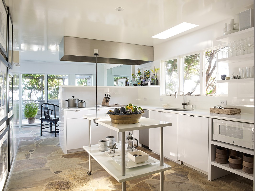 Bright, modern kitchen interior with white cabinets, stainless steel appliances, a kitchen island, and natural light streaming through windows.