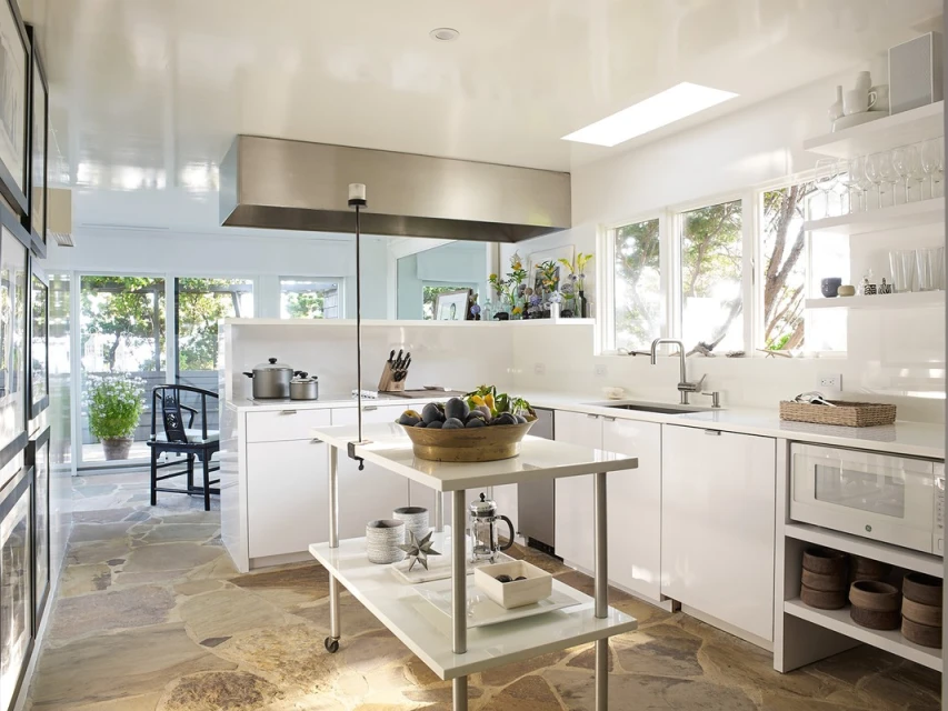 Bright, modern kitchen interior with white cabinets, stainless steel appliances, a kitchen island, and natural light streaming through windows.