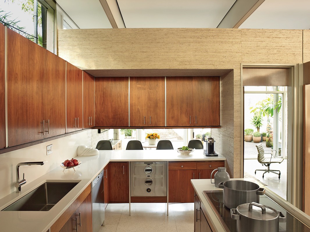 Well-lit modern kitchen features wood cabinets, white countertops, and an open design that merges indoor and outdoor spaces.