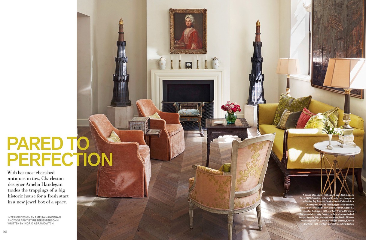 Living room interior with peach armchairs, a yellow sofa, decorative obelisks, a fireplace, and parquet wood flooring in a home setting.
