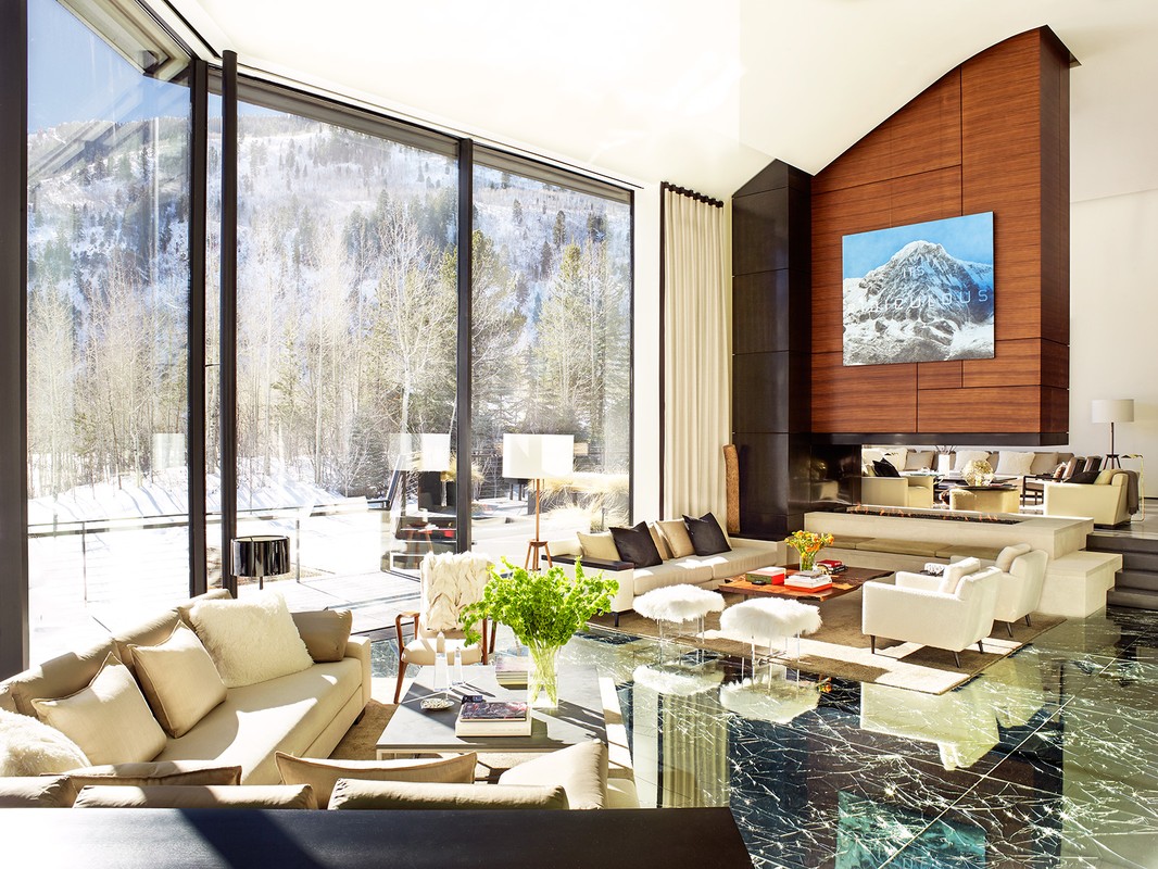 Interior of a modern living room featuring large windows with mountain views, contemporary furniture, and elegant marble flooring.