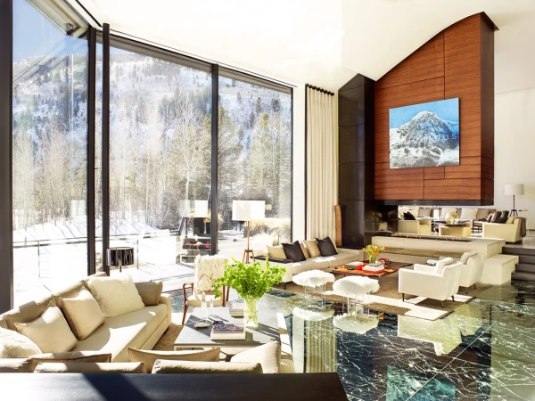 Interior of a modern living room featuring large windows with mountain views, contemporary furniture, and elegant marble flooring.