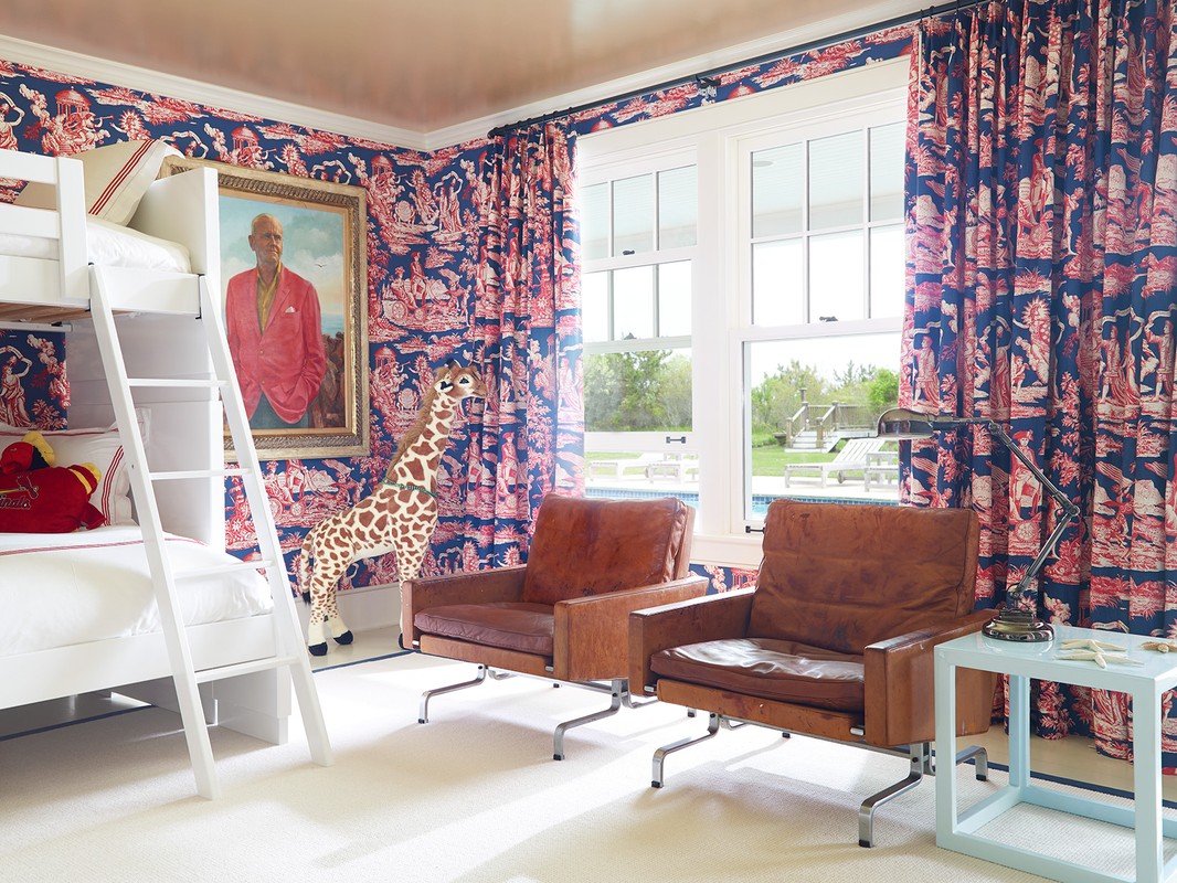 Interior view of a bedroom featuring bunk beds, brown leather armchairs, an animal figurine, and patterned wallpaper and curtains.