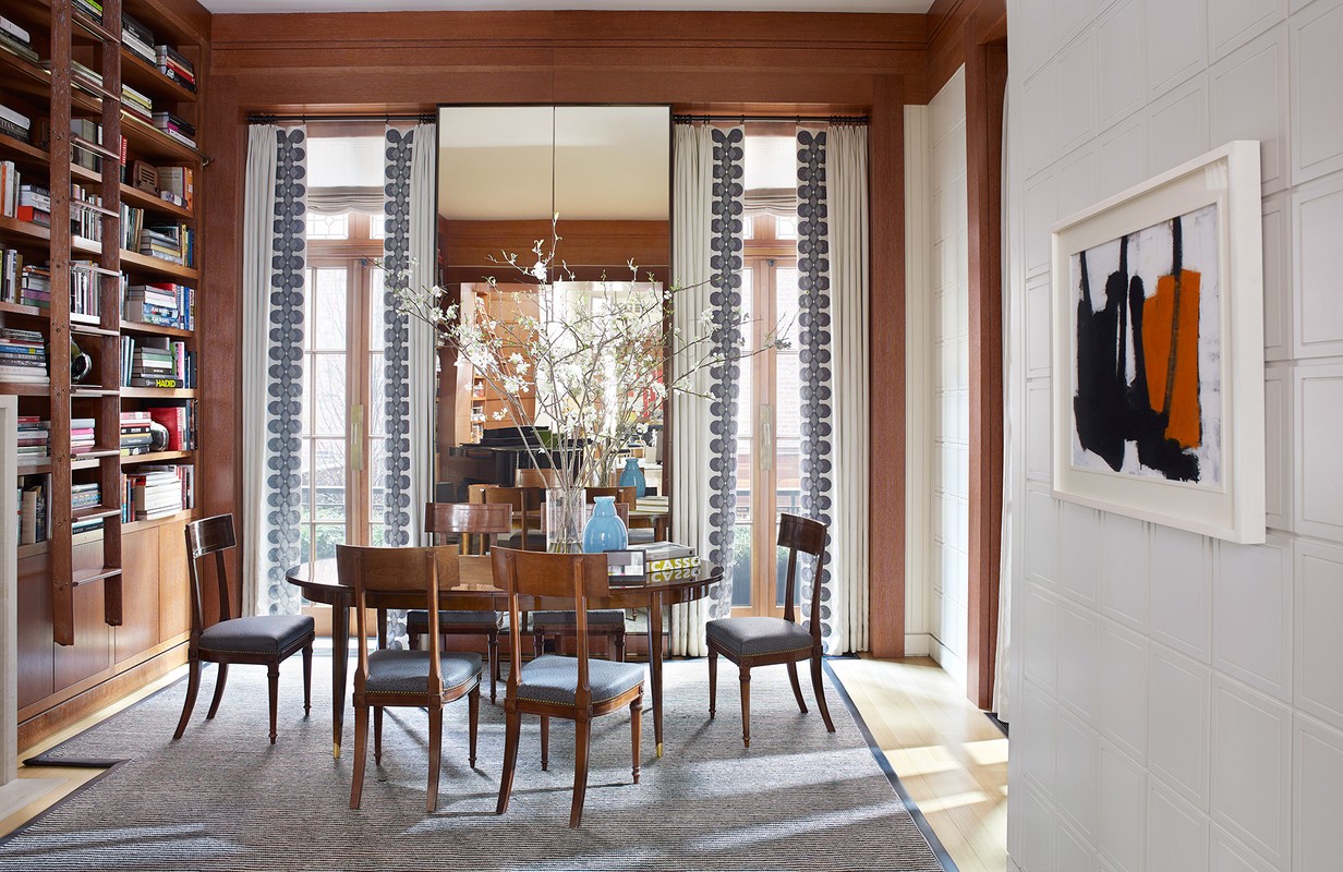 Interior dining room features a wood table surrounded by six chairs, complemented by a bookshelf and abstract wall art. 