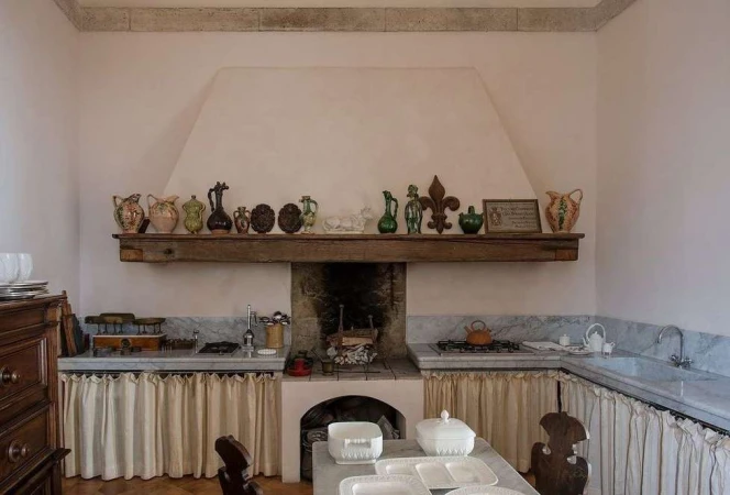 Rustic kitchen interior with farmhouse sink, wooden furniture, antique jugs, vintage cookware, marble countertops and natural light.