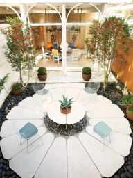 High-angle architectural interior photograph of an open-air courtyard with a petal-shaped patio and modern wire chairs by Pieter Estersohn
