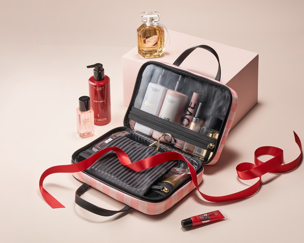 Cosmetic bag filled with beauty products, including perfume, body wash, and lotion, displayed against a neutral backdrop.