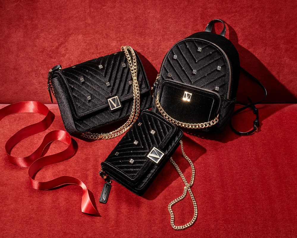 Three black velvet handbags with gold chains are arranged on a red velvet surface, offering a luxurious and fashionable aesthetic.