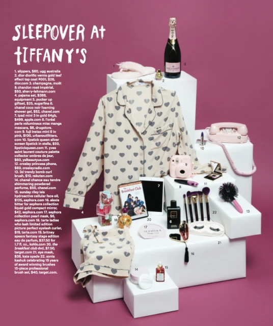 Still life of various beauty and sleepover-themed products, including pajamas, cosmetics, and a telephone, all arranged on white blocks.