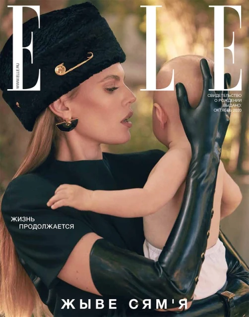 Elle magazine cover featuring a blonde woman in a black hat and gloves holding a baby, showcasing fashion and family themes.