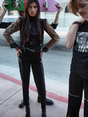 Woman in leopard print jacket and black trousers holding skateboards with two people in Los Angeles, styled by Rafael Linares