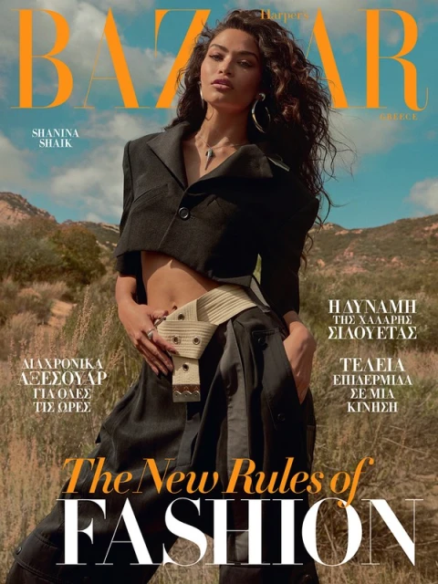 Magazine cover featuring Shanina Shaik in a black outfit with a tan belt, set against a blurred natural landscape backdrop. Harper's Bazaar.