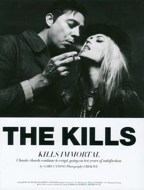 Monochrome image captures a man lighting a cigarette for a stylish woman wearing a hat, with text 'THE KILLS' visible below.