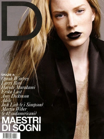 Fashion magazine cover featuring a blonde model with dark lipstick and a black blazer, posing in front of a gray background.