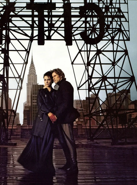 Couple standing on a rooftop with the Chrysler Building in the background, under a metal structure spelling 'CITY'.