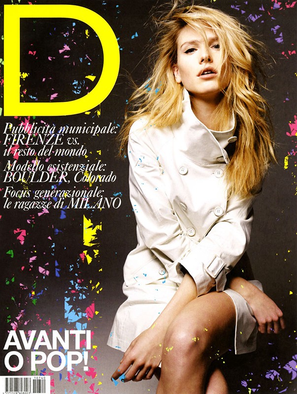 Magazine cover featuring a blonde female model wearing a white jacket, set against a black backdrop with colorful paint splatter.