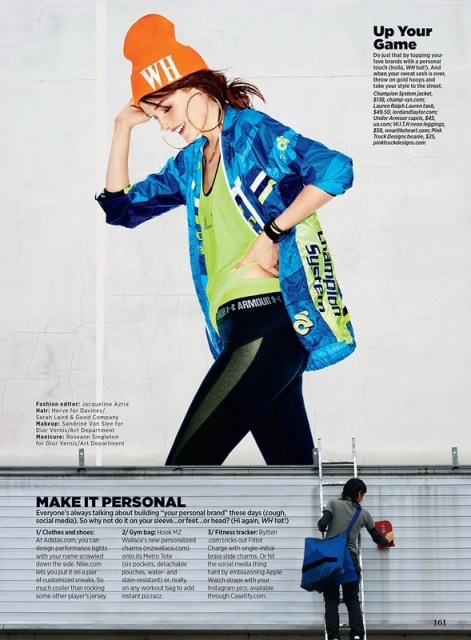 Woman in sporty fashion poses on a billboard for an advertisement, showcasing a vibrant jacket, beanie, tank top, and leggings.