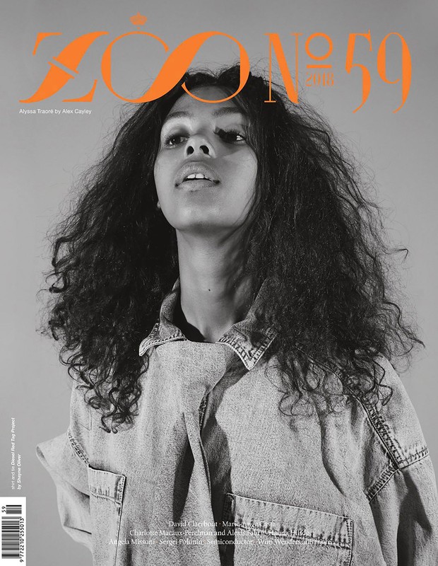 Magazine cover featuring a portrait of a young adult woman with curly hair, wearing a denim jacket, against a grey backdrop.