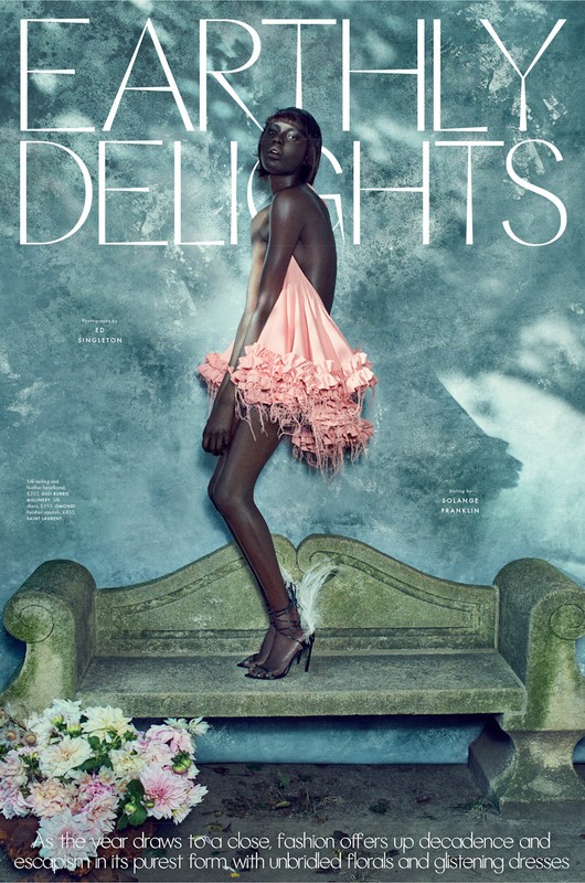 Fashion editorial featuring an African woman in pink dress, posing on a stone bench with flower bouquet against a textured wall.
