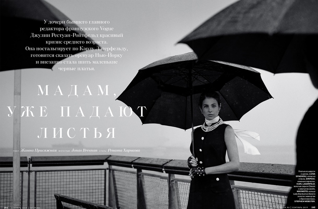 Black and white magazine cover featuring a woman in a dark dress holding an umbrella, pearls, with large text and sea background.