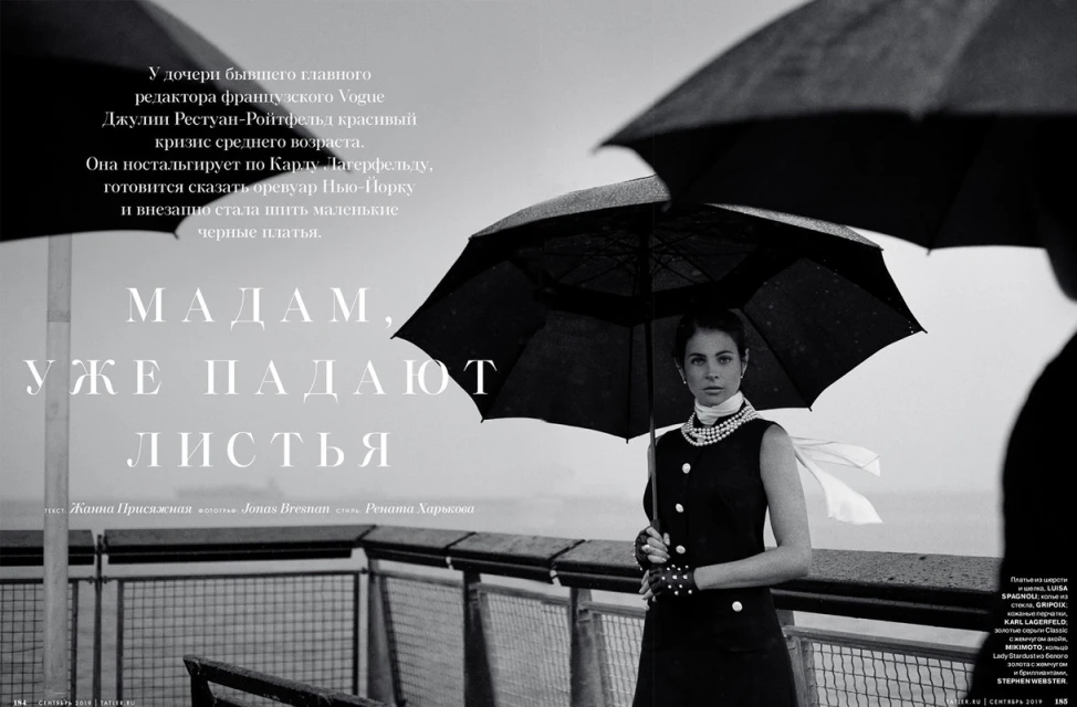 Black and white magazine cover featuring a woman in a dark dress holding an umbrella, pearls, with large text and sea background.