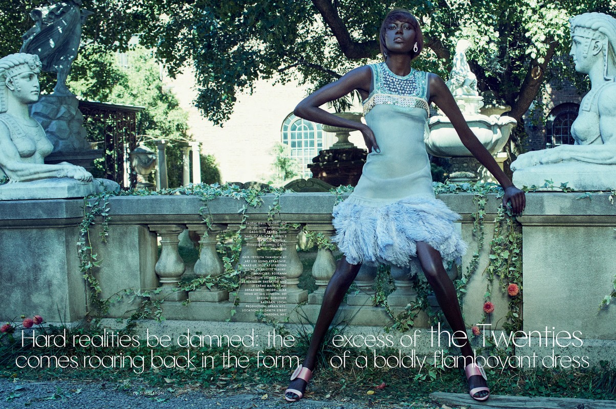 Fashion editorial shot of a slender African woman in a shimmering pastel gown in a garden setting with classic sculptures and greenery.