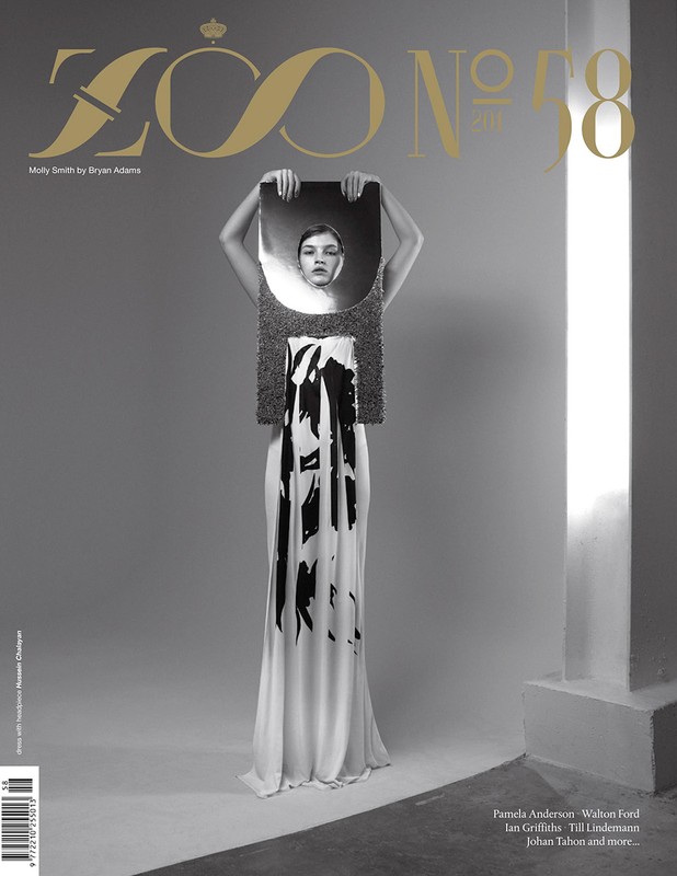 Magazine cover featuring a woman holding a reflective surface over her face, wearing a white dress with dark brushstroke-like patterns.
