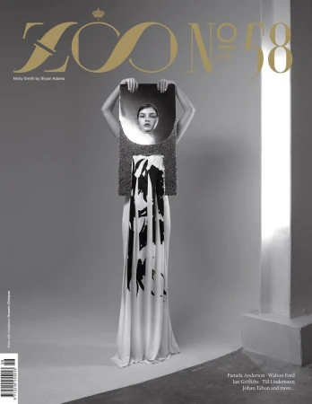 Magazine cover featuring a woman holding a reflective surface over her face, wearing a white dress with dark brushstroke-like patterns.