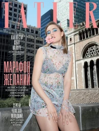 Magazine cover featuring a woman wearing a sheer floral dress and holding a pink flower between her lips against an urban rooftop backdrop.