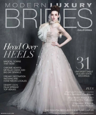 Modern Luxury Brides magazine cover featuring a woman in a wedding gown, feathered collar, and elegant updo against a gray backdrop.