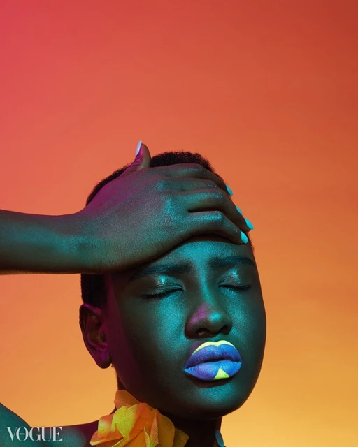 Fashionable portrait of a young woman with closed eyes, colorful makeup, and hand on head, set against a vibrant orange studio backdrop.