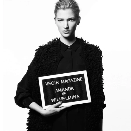 Black and white portrait of a woman holding a felt letter board against a white studio background
