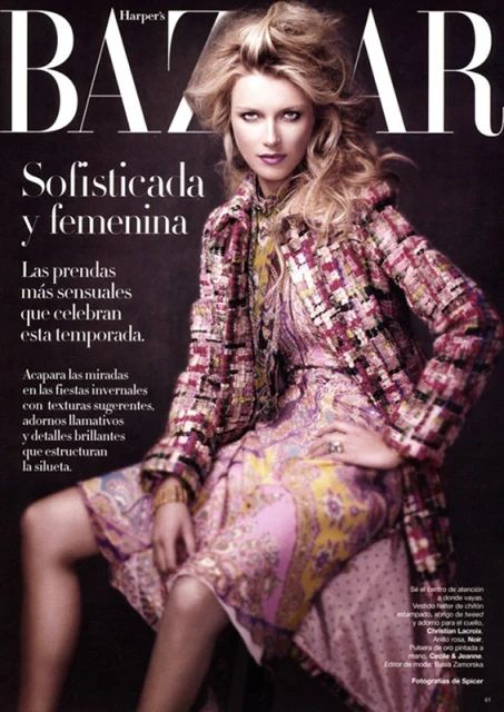 Fashion magazine cover featuring a blonde model in a patterned dress and coat, posing indoors with dark background and magazine text.