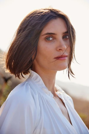 Portrait of a woman with dark bobbed hair wearing a white ruffled blouse outdoors in Los Angeles.