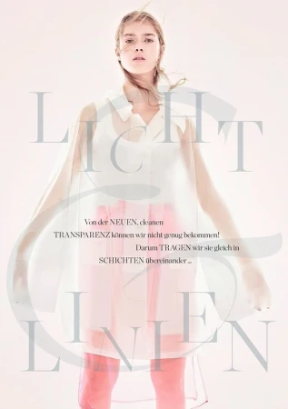 Woman in a sheer top, transparent dress with light pink lining, standing in a light pink room in a fashion editorial photoshoot.