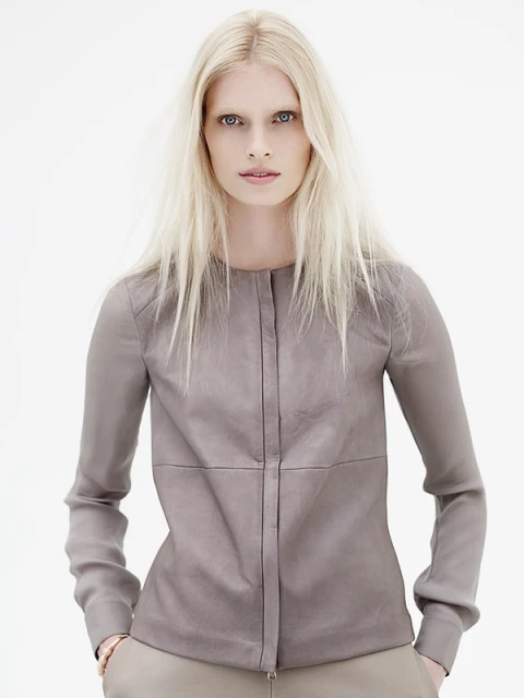 Headshot of a fair-skinned adult female model with long blonde hair wearing a tan-colored, long-sleeved button-down shirt against a white background.