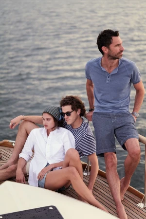 Three models relaxing on a wooden boat deck with an open water background in Los Angeles, styled by Scott Newkirk.