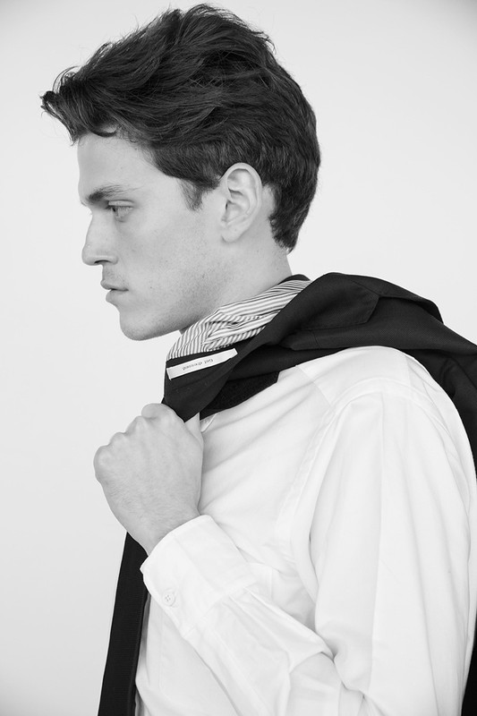 Profile portrait of a man in a white button-down shirt holding a dark jacket over his shoulder, styled by Scott Newkirk.