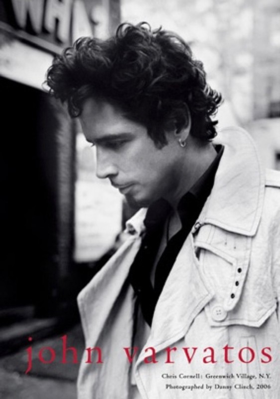 Black-and-white portrait of Chris Cornell in a trench coat against a city backdrop for John Varvatos campaign.