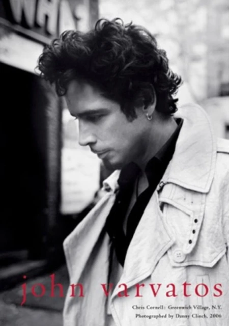 Black-and-white portrait of Chris Cornell in a trench coat against a city backdrop for John Varvatos campaign.