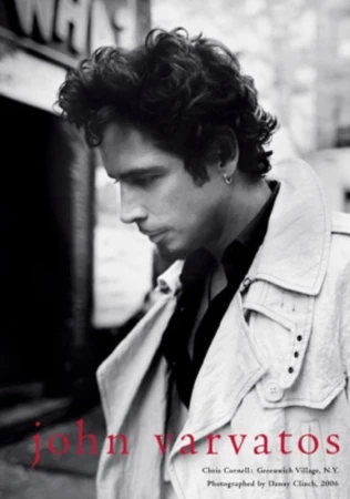 Black-and-white portrait of Chris Cornell in a trench coat against a city backdrop for John Varvatos campaign.