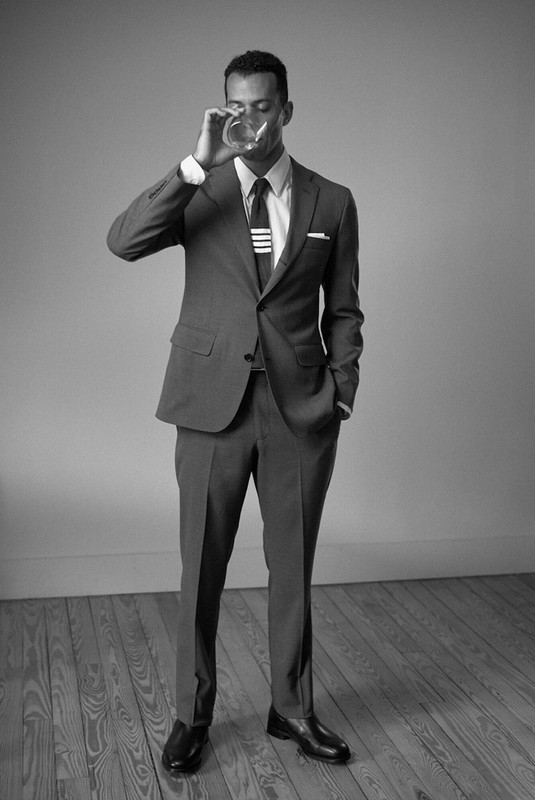 Monochrome portrait of a man in a tailored suit drinking from a glass styled by Scott Newkirk
