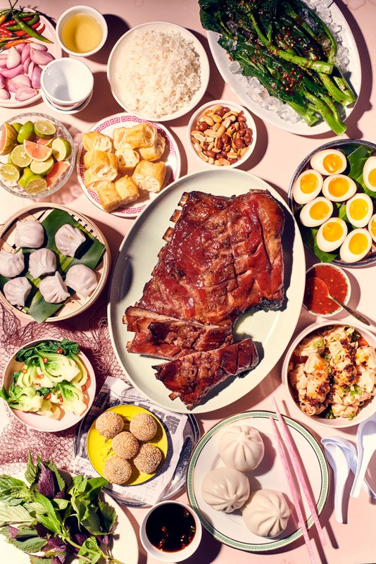 Overhead shot of a table filled with an array of assorted Asian cuisine dishes, including ribs, dumplings, vegetables, and more.