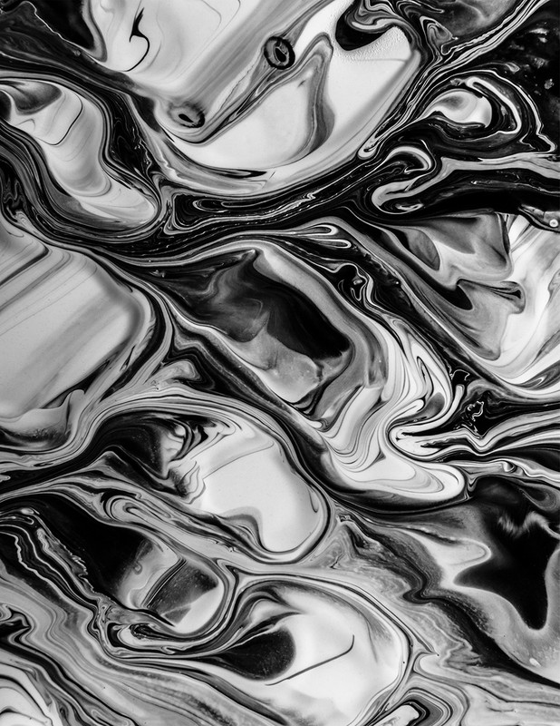 Monochrome abstract swirling pattern of black and white paint mixing, creating a fluid, dynamic design with an organic feel.