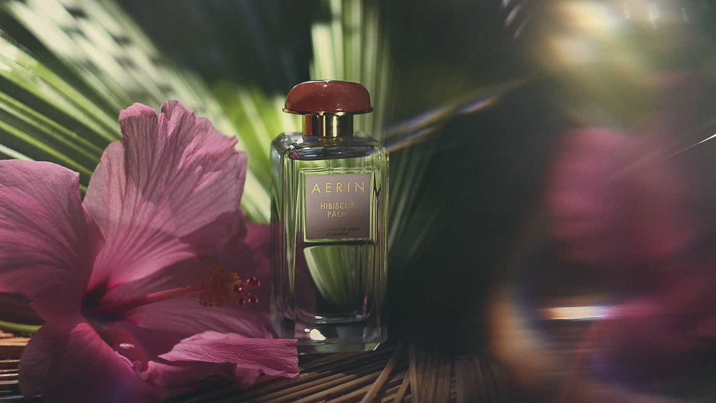 AERIN Hibiscus Palm fragrance bottle with a pink hibiscus and tropical foliage. Product shot for beauty and fashion industries.