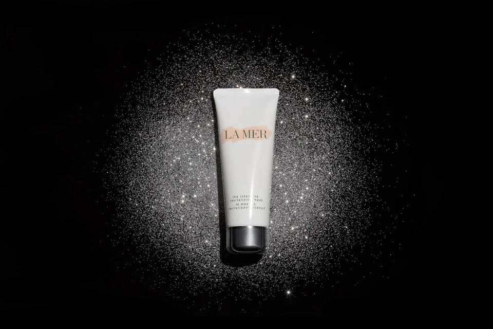 La Mer revitalizing mask tube on black glitter background. Beauty product shot with luxurious feel, studio lit, product focus.